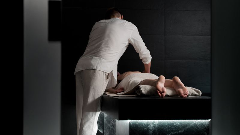 A treatment room with a single low bed and dimmed lighting