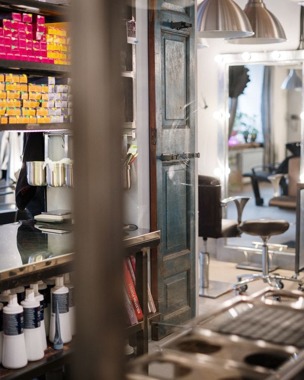 A hair-colour product shelf beside a glimpse of the studio floor through an open door