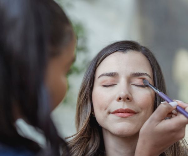 A makeup artist applying eyeshadow during a natural daytime look
