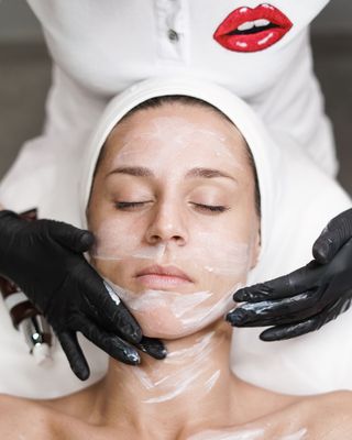 A beautician removing a clay mask after a facial