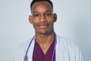 A doctor in scrubs and a white coat